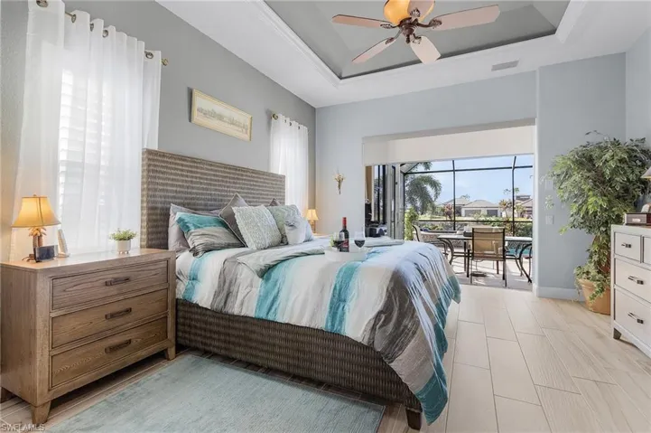 Bedroom featuring access to exterior, ceiling fan, and a raised ceiling