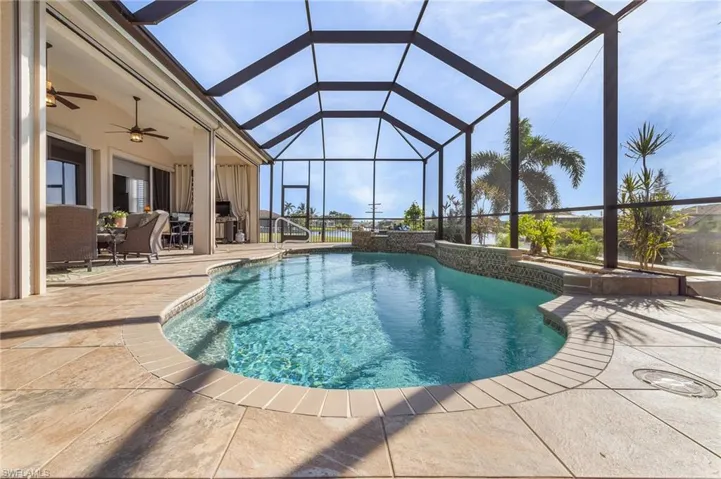View of swimming pool with glass enclosure, ceiling fan, and a patio area