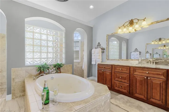 Bathroom featuring vanity, tiled tub, and crown molding