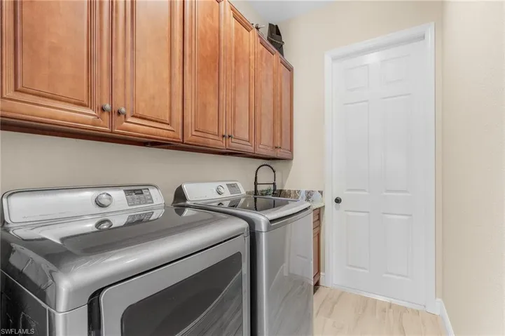 Clothes washing area featuring cabinets, light hardwood / wood-style floors, and washer and clothes dryer