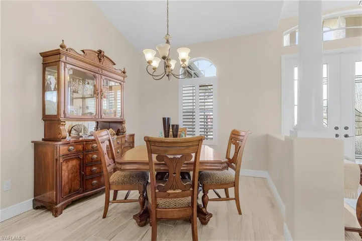 Dining space featuring light wood-type flooring, a chandelier, and vaulted ceiling