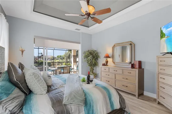 Bedroom featuring a raised ceiling, access to exterior, ceiling fan, and light hardwood / wood-style flooring