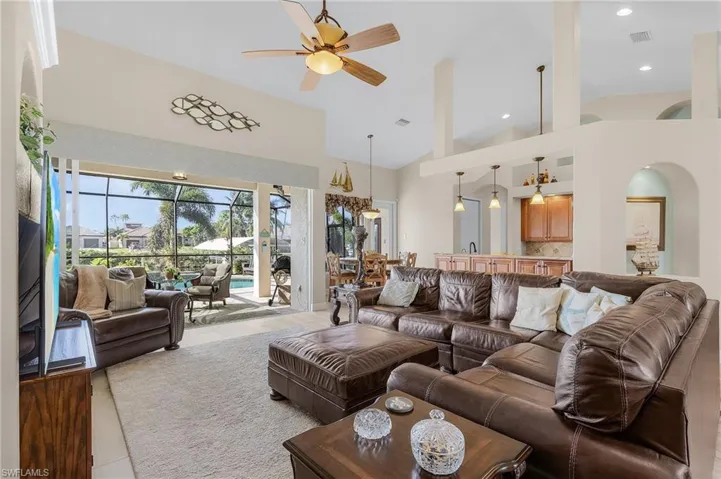 Living room with ceiling fan, light tile patterned floors, and high vaulted ceiling