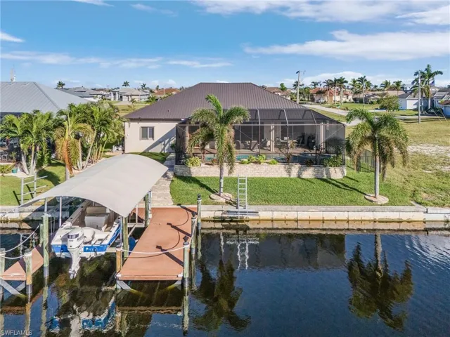 View of dock featuring a lanai, a yard, and a water view