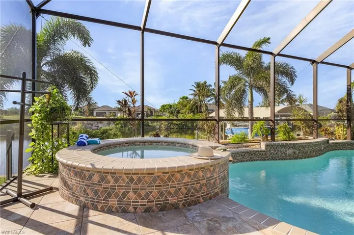 View of pool featuring glass enclosure and an in ground hot tub