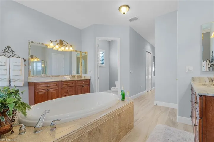 Bathroom with tiled bath, vanity, and toilet