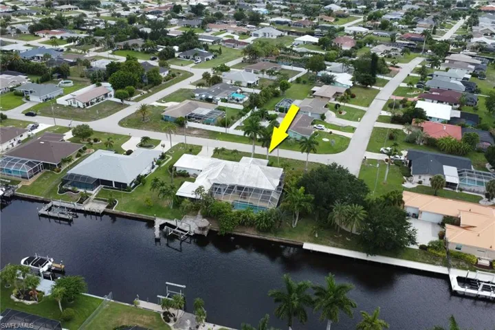 Waterfront property featuring a screened-in pool enclosure, private dock, and mature palm trees
