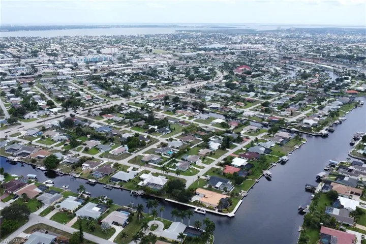 Canal-front community featuring residential properties, mature palm trees, and a distant body of water