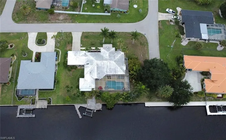 Waterfront property featuring a private boat dock, screened-in swimming pool, and a paved driveway
