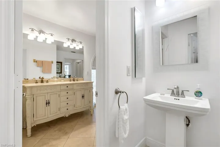 Pedestal sink with chrome faucet and framed mirror