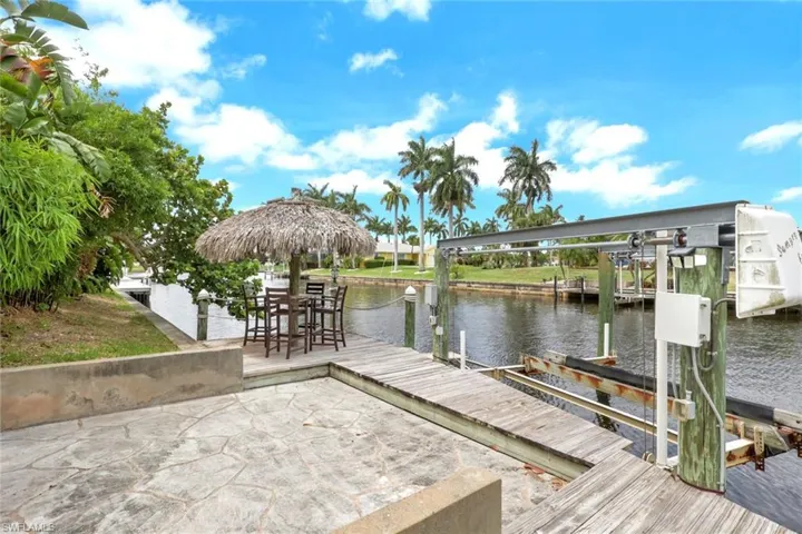 Waterfront property featuring a private boat lift, a wood dock, and a stone patio