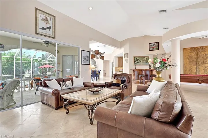 Spacious living area featuring large format tile flooring and vaulted ceilings