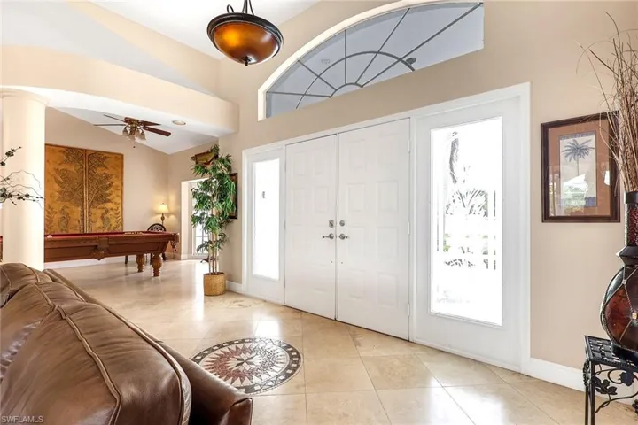 Grand entryway featuring double doors with sidelights, a large arched transom window, and a prominent pendant light fixture