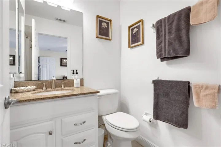 White vanity with a stone-finish countertop and undermount sink