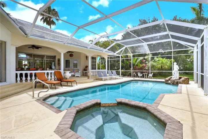 Screen-enclosed pool area featuring a large swimming pool, integrated spa, and a rock waterfall feature