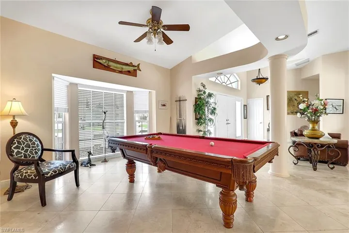 Spacious room featuring neutral wall tones, large bay windows with horizontal blinds, and a tray ceiling with recessed lighting
