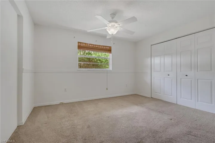 Unfurnished bedroom with carpet, a closet, ceiling fan, and a textured ceiling