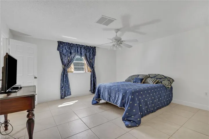 Bedroom with a textured ceiling, ceiling fan, and light tile patterned floors