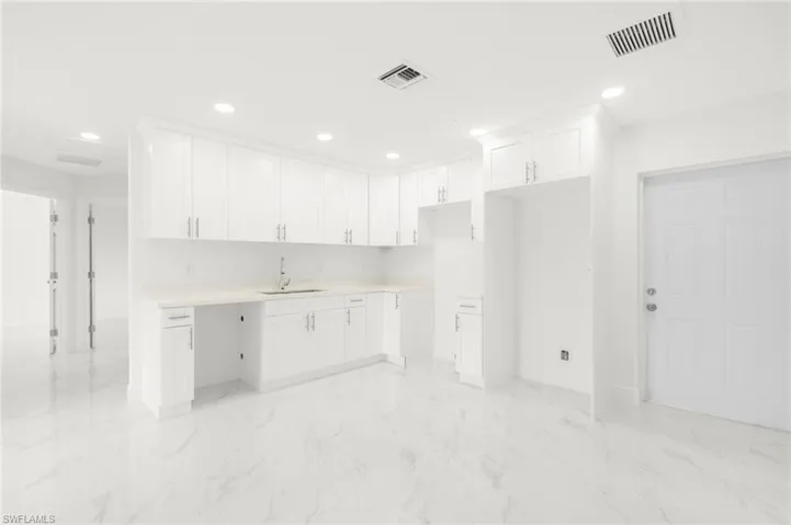 Kitchen with sink, white cabinets, and light tile patterned floors