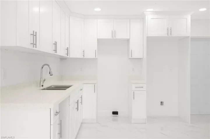 Kitchen with sink, white cabinets, and light tile patterned floors