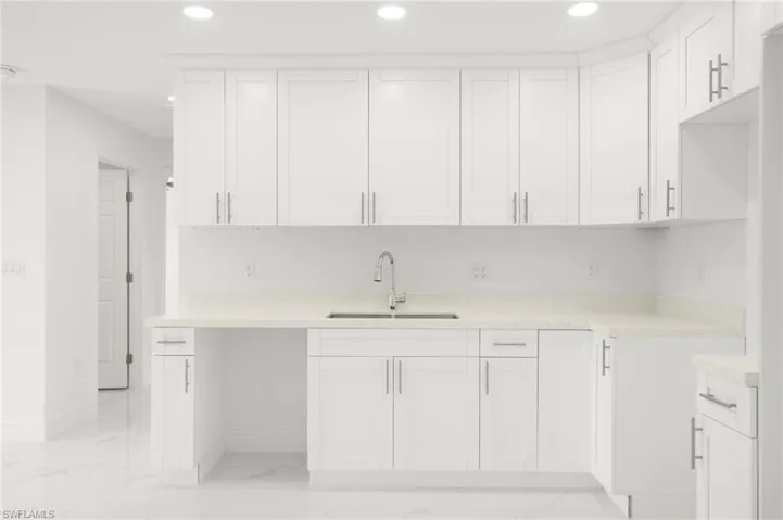 Kitchen featuring sink, white cabinetry, light tile patterned floors, and light stone countertops