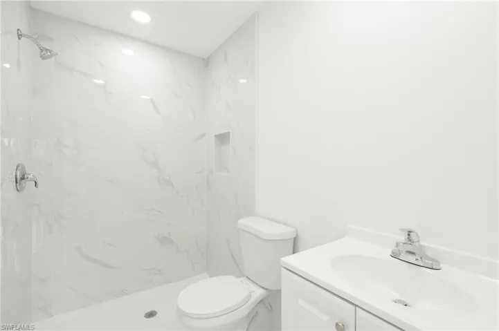 Bathroom with vanity, tiled shower, and toilet
