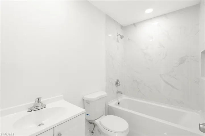 Full bathroom with vanity, tiled shower / bath combo, and toilet