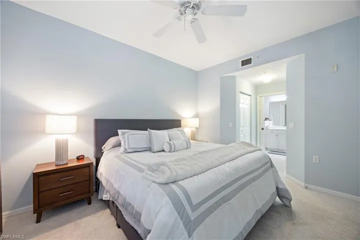 Carpeted bedroom with ensuite bathroom and ceiling fan