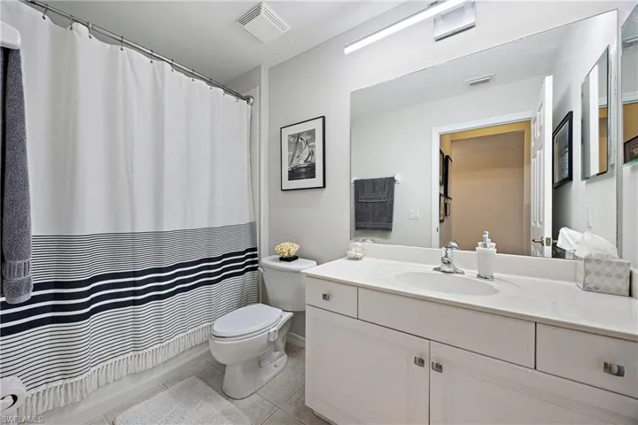 Full bathroom with vanity, shower / bathtub combination with curtain, toilet, and tile patterned floors