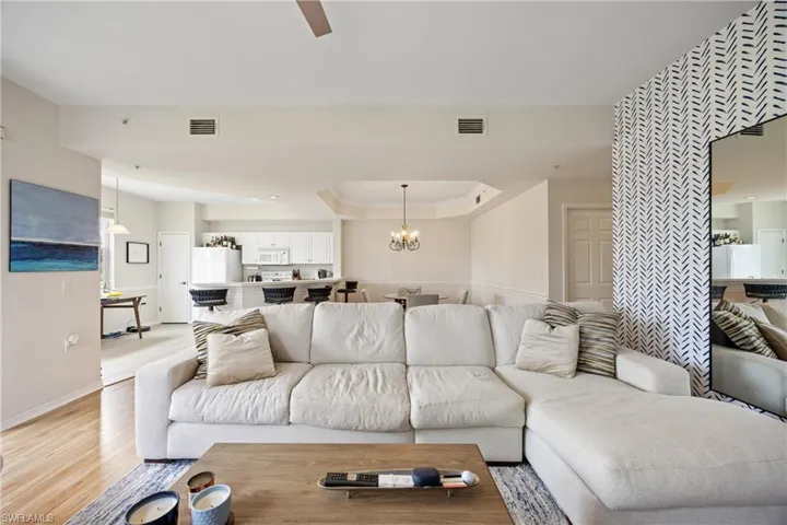 Living room with light hardwood / wood-style flooring and ceiling fan with notable chandelier