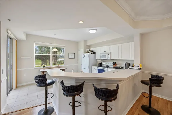 Kitchen with bar stools, and breakfast bar, lighting, and white cabinets