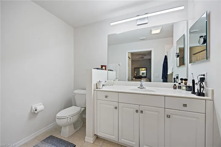 Bathroom featuring vanity, toilet, tile patterned floors, and ceiling fan