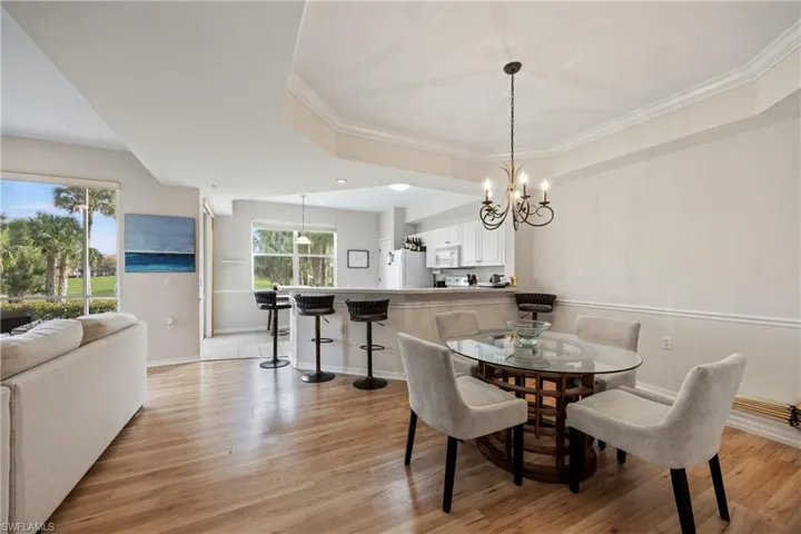 Dining room with crown molding, a notable chandelier, and light wood-type flooring
