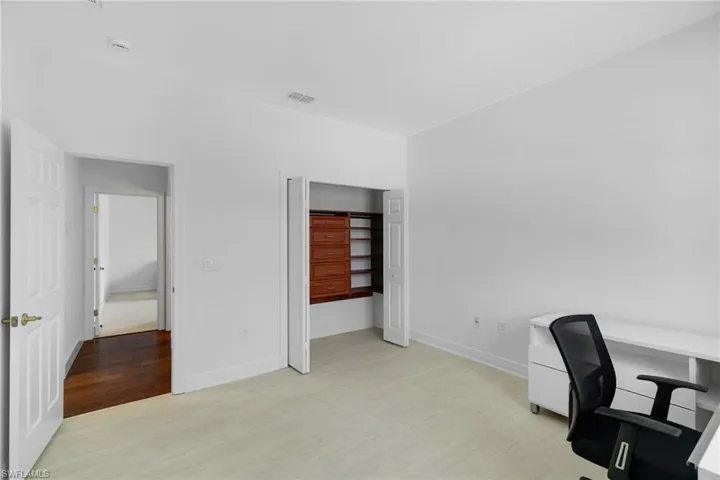 Clean, modern space featuring light-toned vinyl plank flooring, crisp white walls, recessed lighting, and a bi-fold closet with custom built-ins.