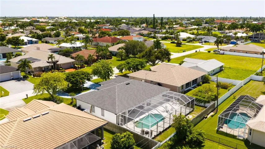 Residential property featuring a screened-in swimming pool and established landscaping