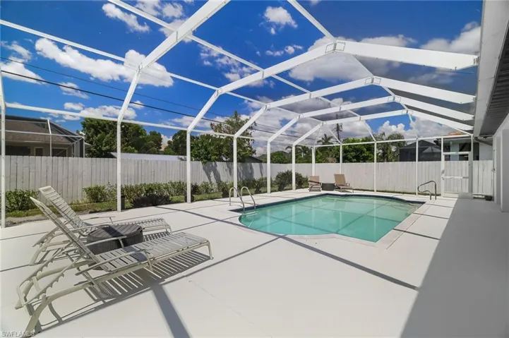 Fully screened pool space framed by a spacious concrete deck, integrated steps, and a secure white privacy fence.