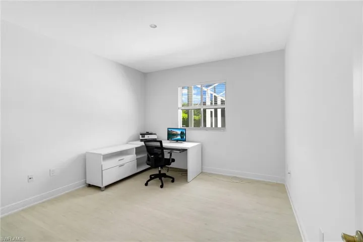 Bright space anchored by light vinyl plank floors, recessed lighting and a window with custom blinds.
