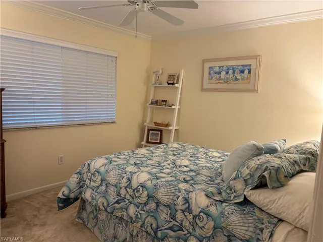 Bedroom with ornamental molding, light colored carpet, and a ceiling fan
