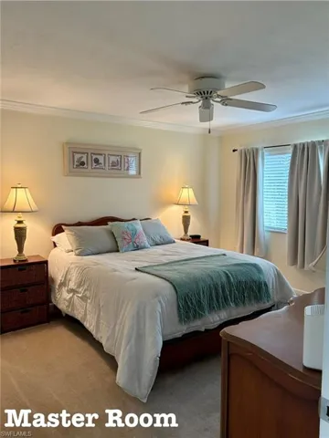 Carpeted bedroom featuring crown molding and a ceiling fan