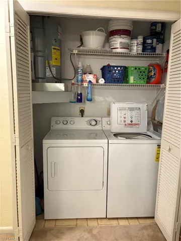 Laundry area featuring independent washer and dryer, water heater, and light carpet