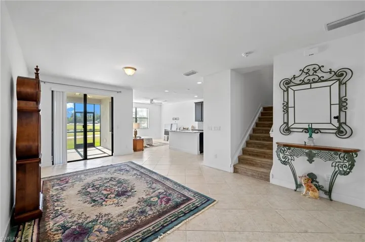 Foyer entrance featuring light tile patterned floors, visible vents, stairs, and baseboards