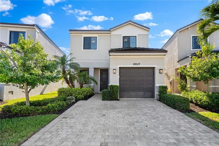 View of front of house with stucco siding, decorative driveway, and a garage