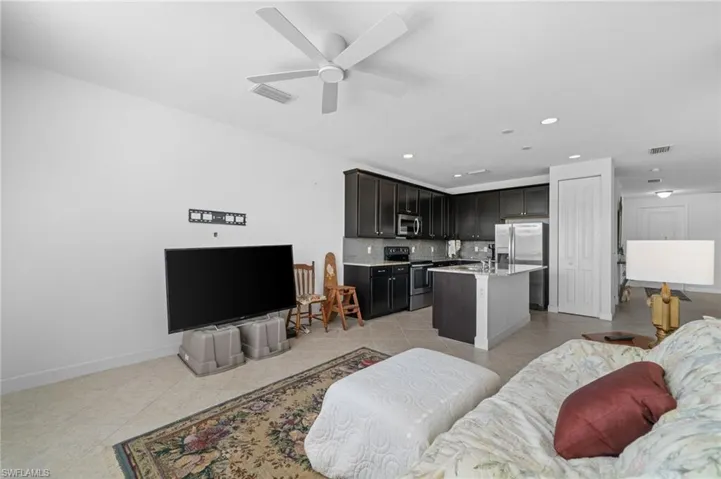 Living room featuring light tile patterned flooring, visible vents, and ceiling fan