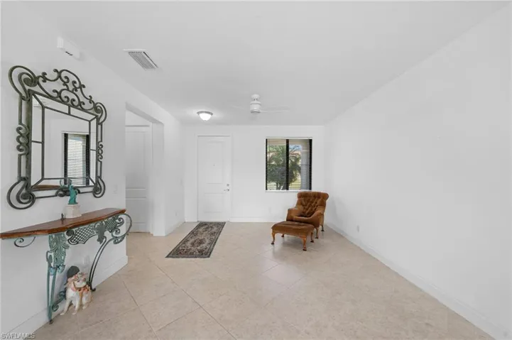 Foyer featuring light tile patterned floors, a ceiling fan, visible vents, and baseboards