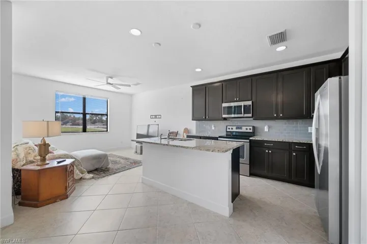 Kitchen featuring visible vents, tasteful backsplash, stainless steel appliances, light stone countertops, and ceiling fan