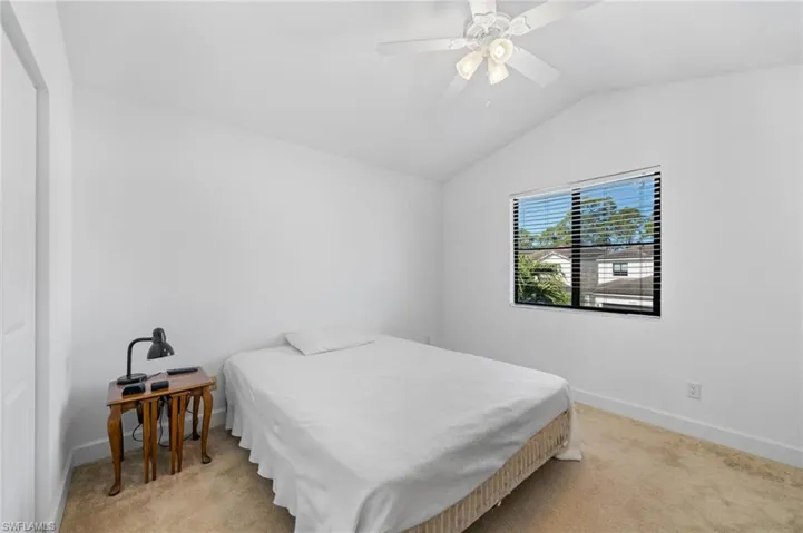 Bedroom with light colored carpet, baseboards, lofted ceiling, and ceiling fan