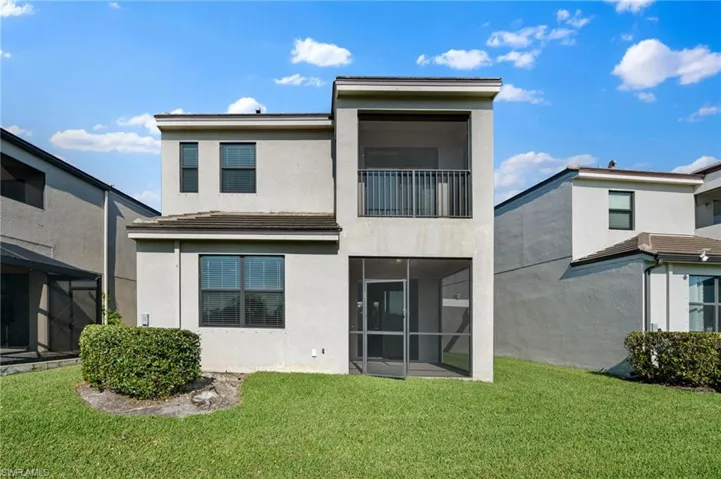 Rear view of house with stucco siding and a lawn