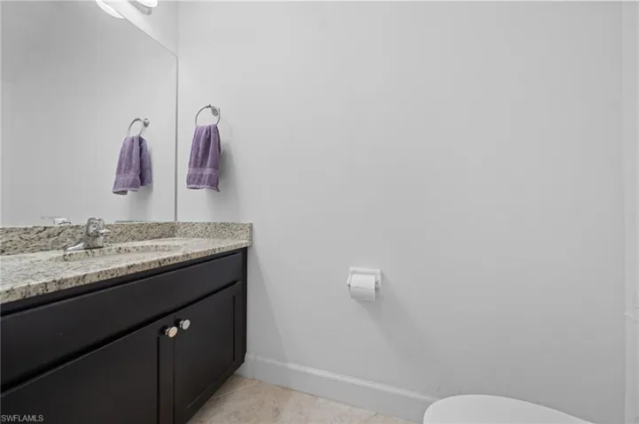 Half bathroom featuring baseboards, toilet, vanity, and tile patterned flooring