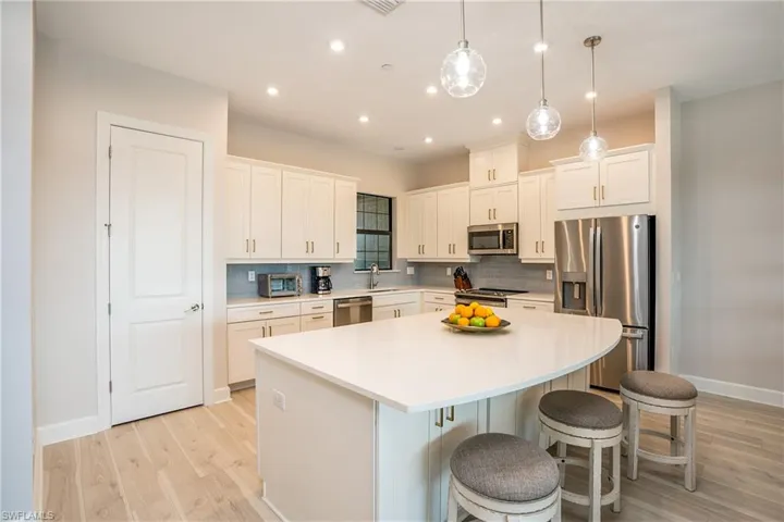 Kitchen featuring stainless steel appliances, light wood-style floors, tasteful backsplash, a center island, and recessed lighting