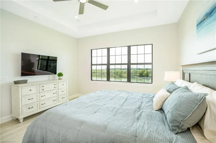 Bedroom with light wood-style flooring, a raised ceiling, ceiling fan, and recessed lighting